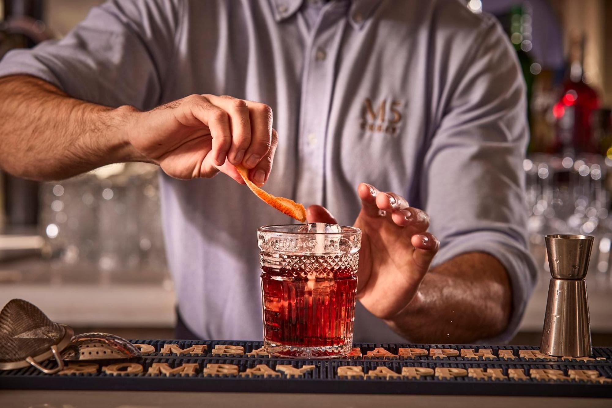 Hotel Cort Palma de Mallorca Exterior foto A bartender garnishes a Negroni with an orange peel.